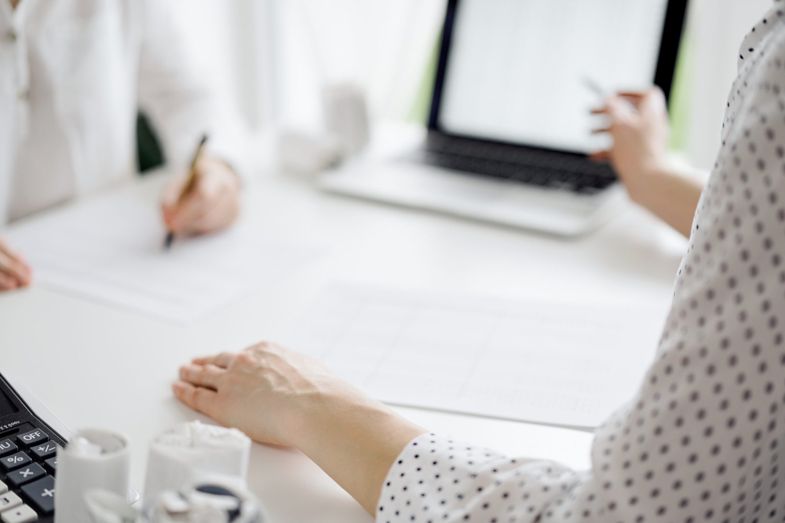 Two accountants using a laptop computer for counting taxes at white desk in office. Business Woman pointing into screen with a pen. Teamwork in business audit and finance.